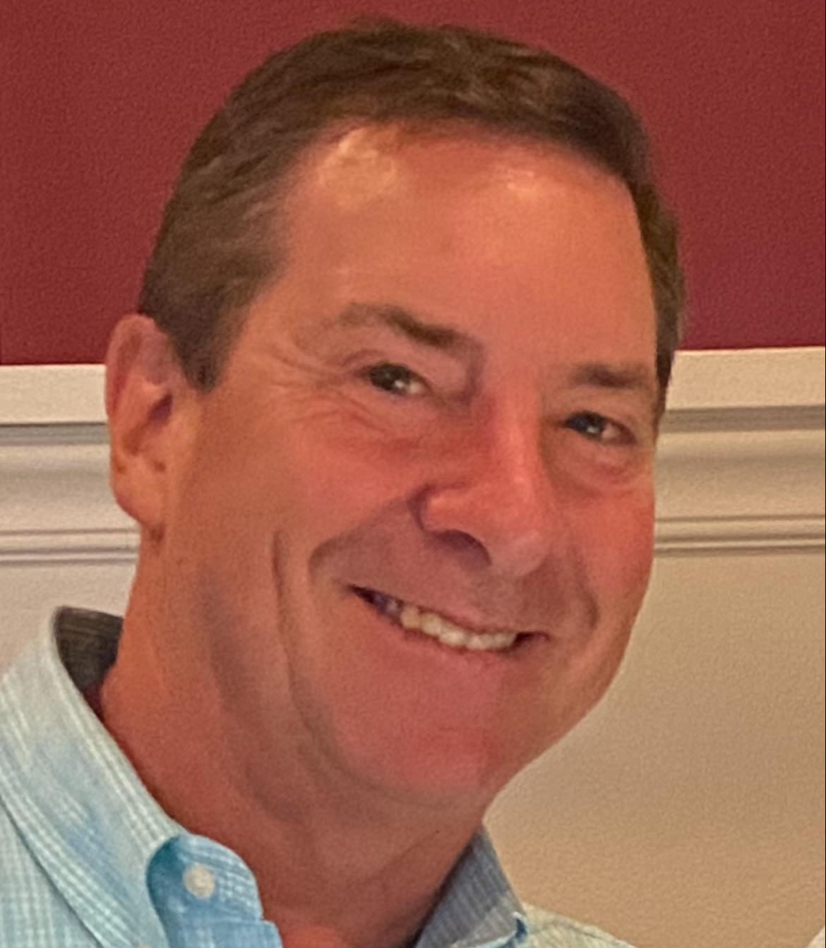 James P. Covey smiling, wearing a light blue shirt.